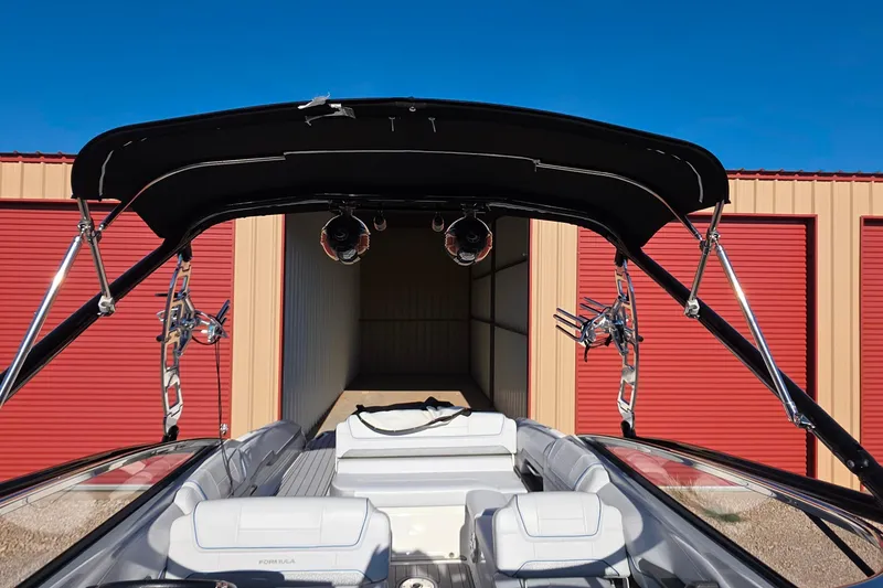 Slide: The Image of 2021 Formula 270 Bowrider boat with bimini top, parked near red storage units. - 20