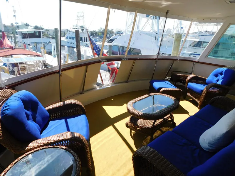 Slide: The Image of 1987 Hatteras 54 Motoryacht interior with blue cushioned wicker seating and glass tables. - 11