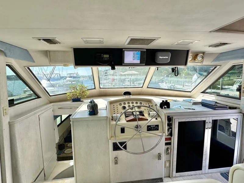 Slide: The Image of 1987 Hatteras 54 Motoryacht helm with steering wheel, navigation equipment, and panoramic windows. - 19
