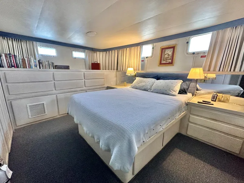 Slide: The Image of 1987 Hatteras 54 Motoryacht bedroom with double bed, lamps, and storage cabinets. - 24