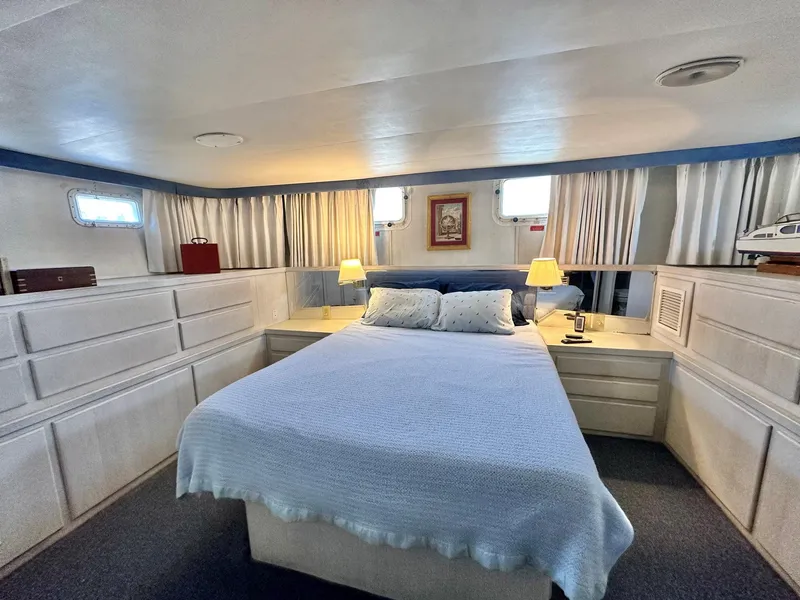Slide: The Image of 1987 Hatteras 54 Motoryacht bedroom with cozy bed, lamps, and nautical decor. - 25