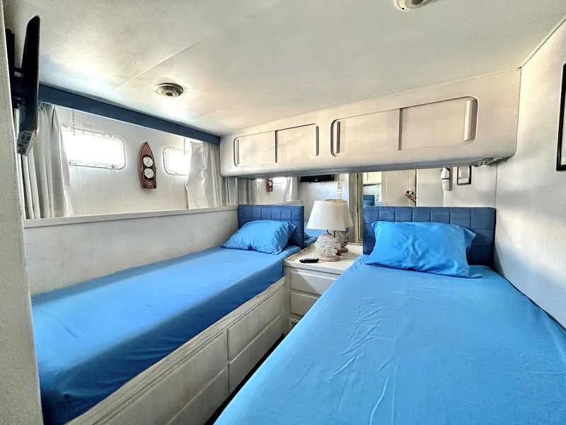 Slide: The Image of Twin cabin with blue bedding in 1987 Hatteras 54 Motoryacht, featuring storage and natural light. - 29