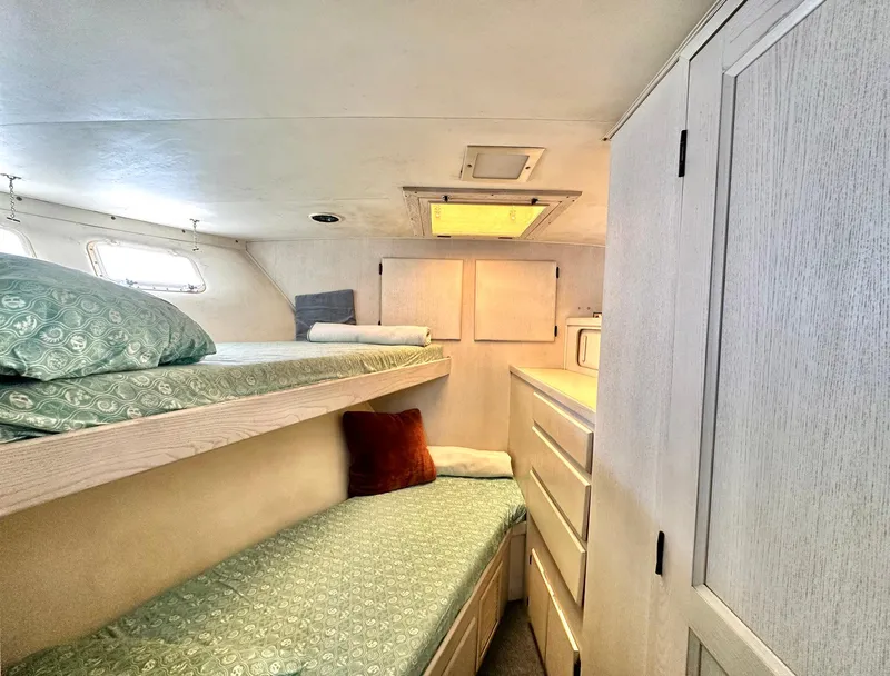 Slide: The Image of 1987 Hatteras 54 Motoryacht cabin with bunk beds, storage, and natural light. - 32