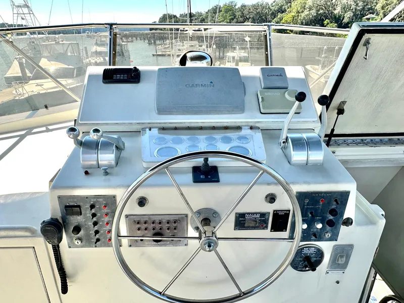 Slide: The Image of 1987 Hatteras 54 Motoryacht helm with steering wheel and control panel, docked at marina. - 36