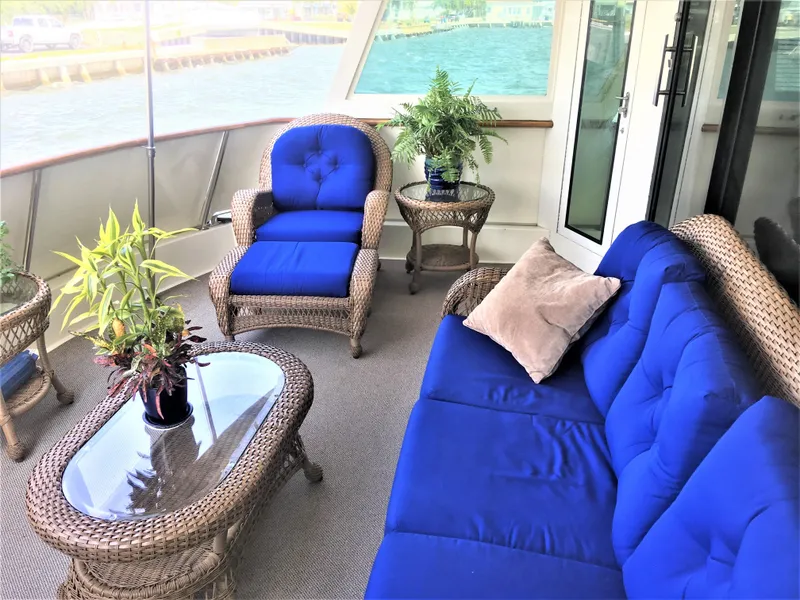 Slide: The Image of Luxurious 1987 Hatteras 54 Motoryacht deck with blue-cushioned wicker furniture and potted plants. - 7