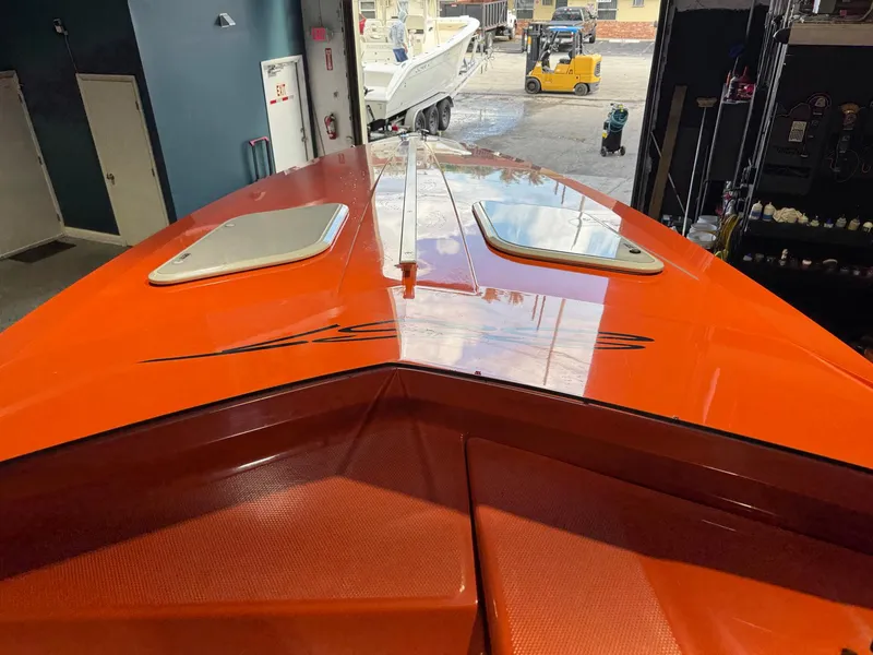 Slide: The Image of 2007 Baja 35 Outlaw boat with vibrant orange deck in a garage setting. - 28