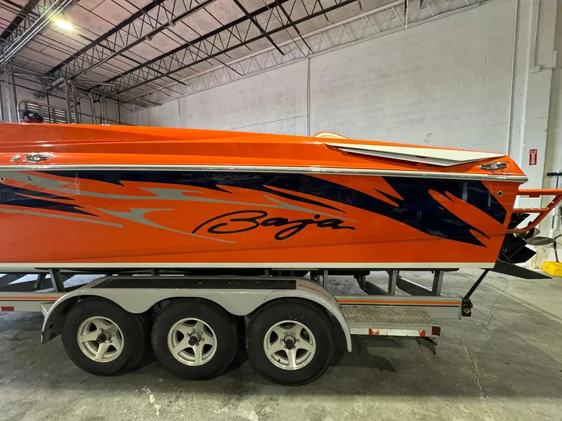 Slide: The Image of 2007 Baja 35 Outlaw boat with vibrant orange and blue design on a trailer. - 31