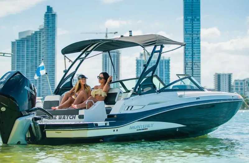 Slide: The Image of 2020 Monterey M45 boat with two people relaxing, city skyline in background. - 1