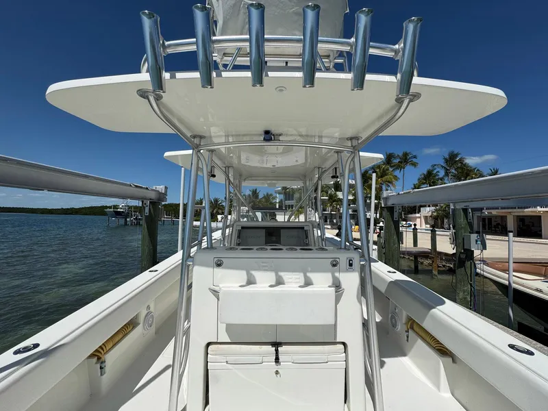 Slide: The Image of 2014 SeaVee 390B Center Console boat docked, showcasing helm and rod holders under clear blue sky. - 15