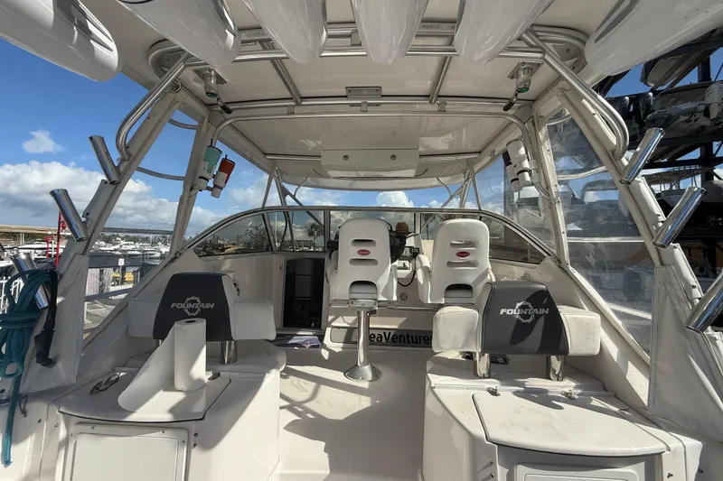 Slide: The Image of 2017 Fountain 38 Sportfish Cruiser interior with seating and helm, docked under sunny skies. - 20