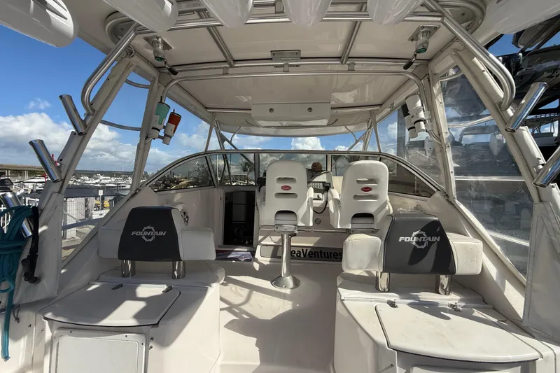 Slide: The Image of 2017 Fountain 38 Sportfish Cruiser interior with seating and helm, docked under clear skies. - 25
