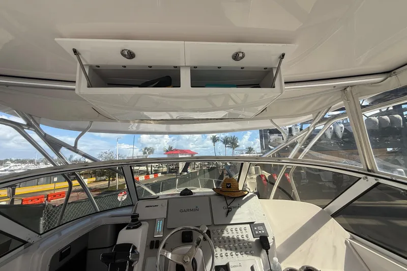 Slide: The Image of 2017 Fountain 38 Sportfish Cruiser helm with Garmin navigation, open storage, and marina view. - 33