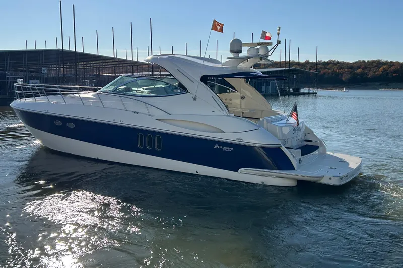 Slide: The Image of 2005 Cruisers 500 yacht on water, featuring sleek design and flags, near marina. - 2