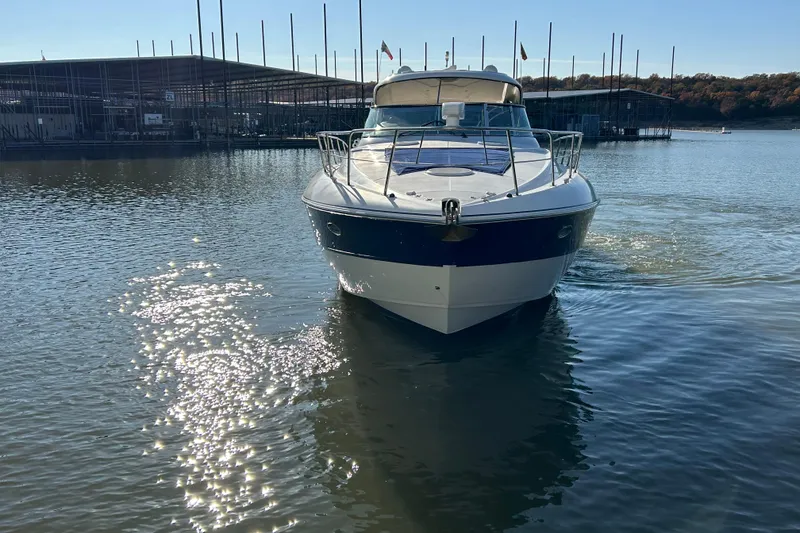Slide: The Image of 2005 Cruisers 500 yacht on calm water near marina, reflecting sunlight. - 38