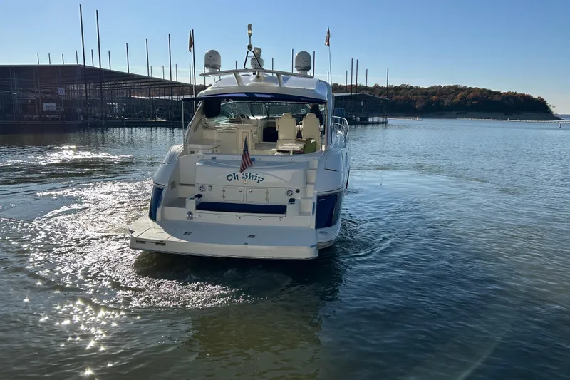 Slide: The Image of Cruisers 500 yacht from 2005 on a serene lake, docked near a marina. - 44