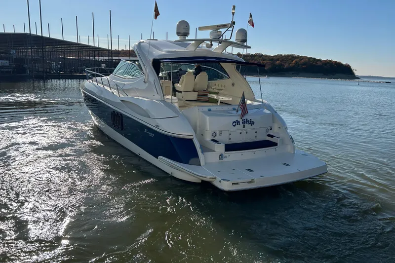 Slide: The Image of 2005 Cruisers 500 yacht on water, rear view, sunny day, flags displayed. - 45
