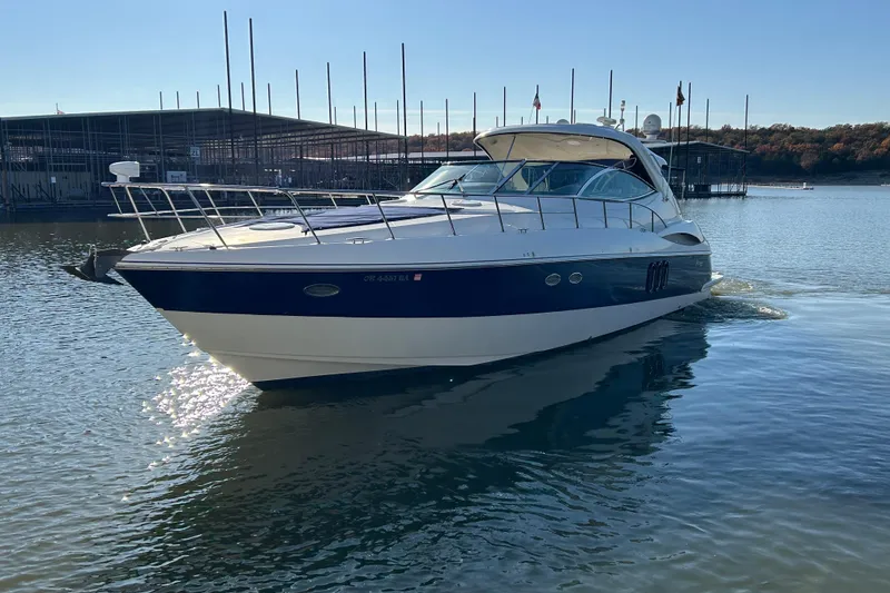 Slide: The Image of 2005 Cruisers 500 yacht on calm water near a marina, under clear blue sky. - 36