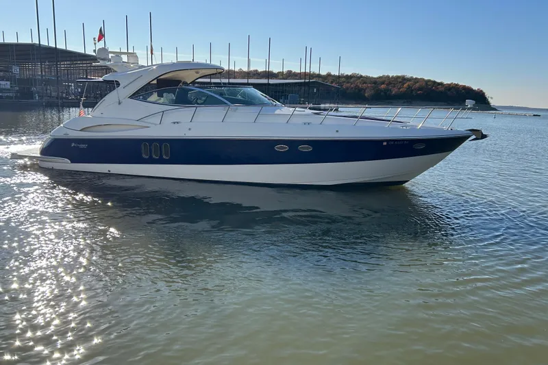 Slide: The Image of 2005 Cruisers 500 yacht on calm water, reflecting sunlight, with marina in background. - 42