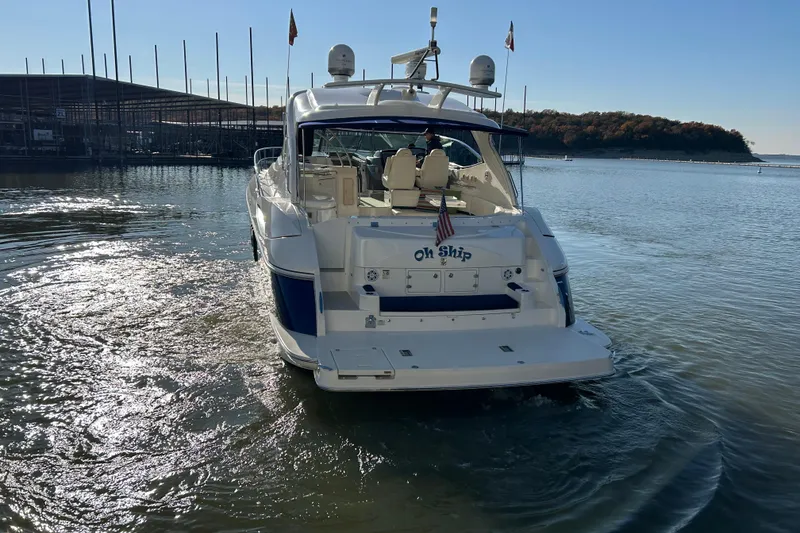 Slide: The Image of 2005 Cruisers 500 yacht on calm water, rear view with flags and marina backdrop. - 6