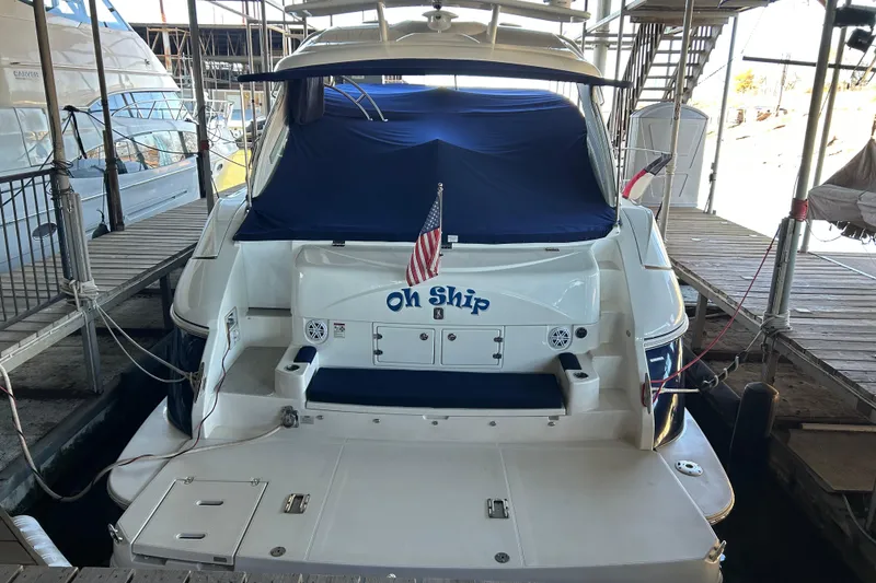 Slide: The Image of 2005 Cruisers 500 yacht docked, rear view with "Oh Ship" name and American flag. - 9