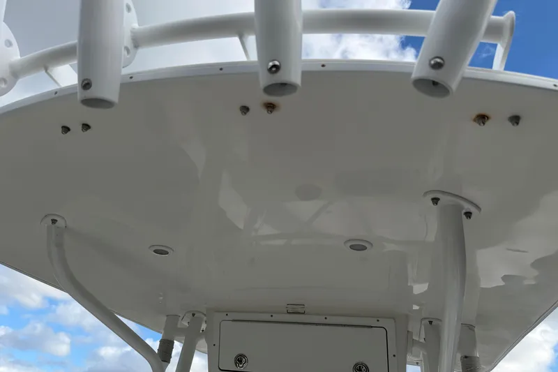 Slide: The Image of 2004 Regulator 24 Forward Seating boat's T-top with rod holders against blue sky. - 11