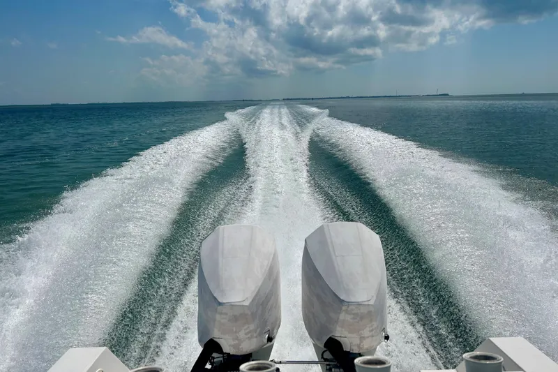 Slide: The Image of 2004 Regulator 24 Forward Seating boat cruising on open water, leaving a wake trail. - 9