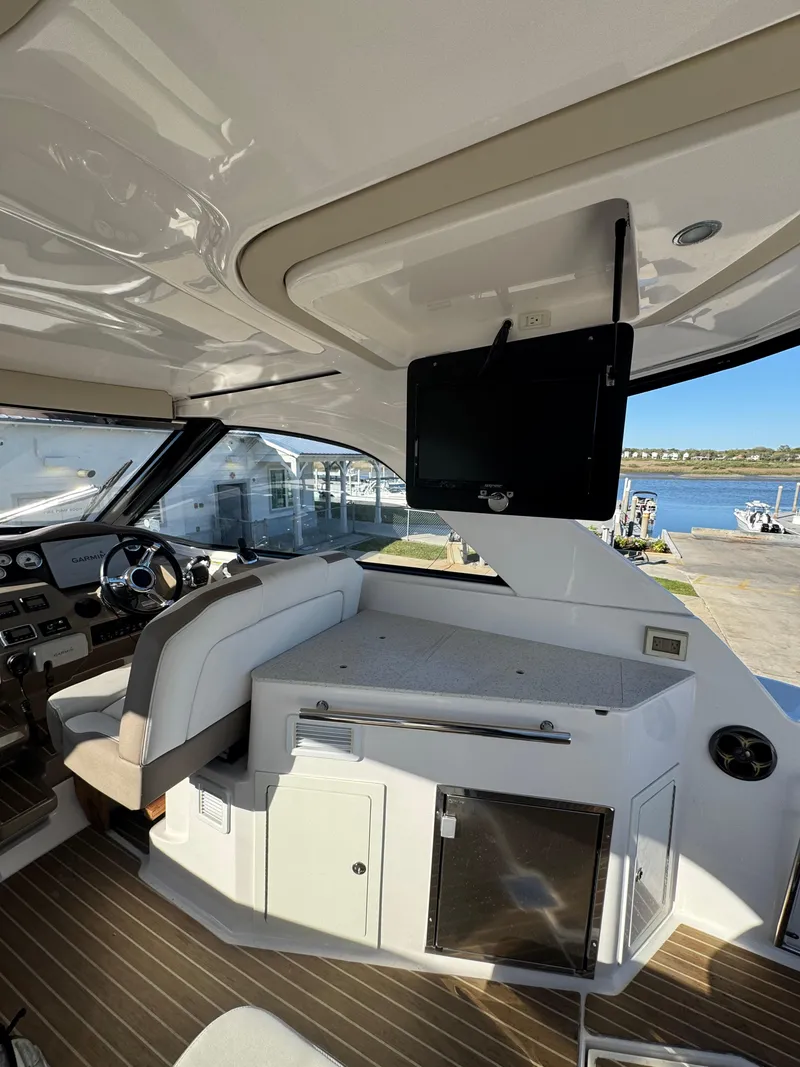Slide: The Image of 2016 Regal 35 Sport Coupe interior with seating, TV, and waterfront view. - 19