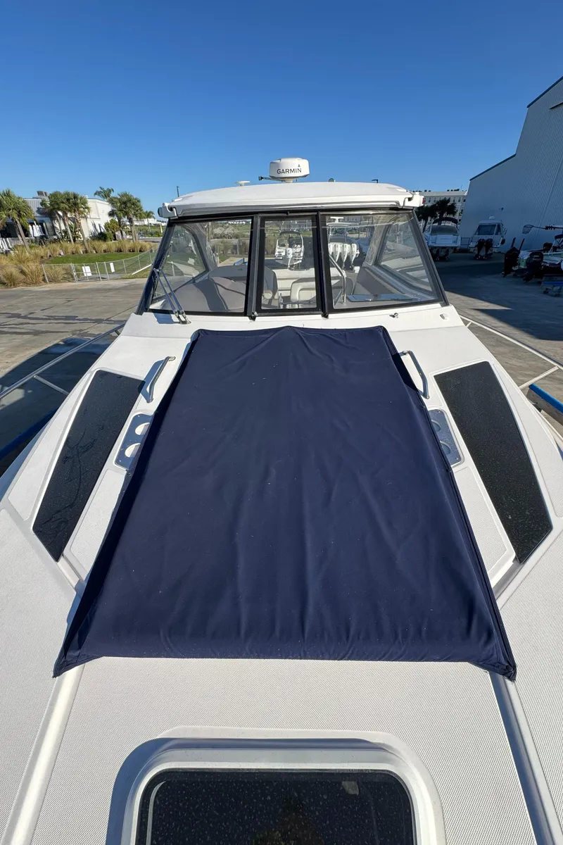 Slide: The Image of 2016 Regal 35 Sport Coupe boat with sunpad, docked under clear blue sky. - 21