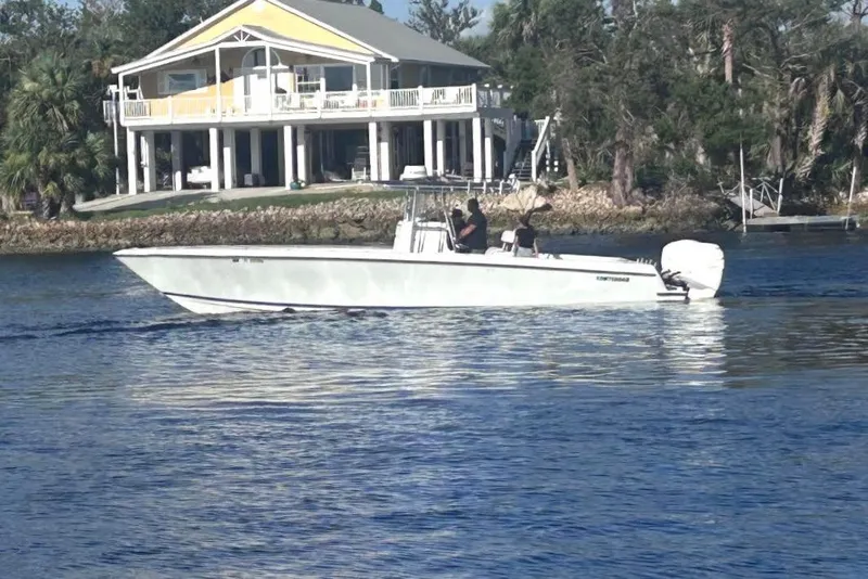 The Image of 2005 Contender 35 ST boat cruising on a calm river near a waterfront house. - 0