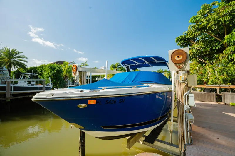 Slide: The Image of 2021 Monterey 255SS Super Sport boat docked, covered in blue tarp, surrounded by lush greenery. - 2