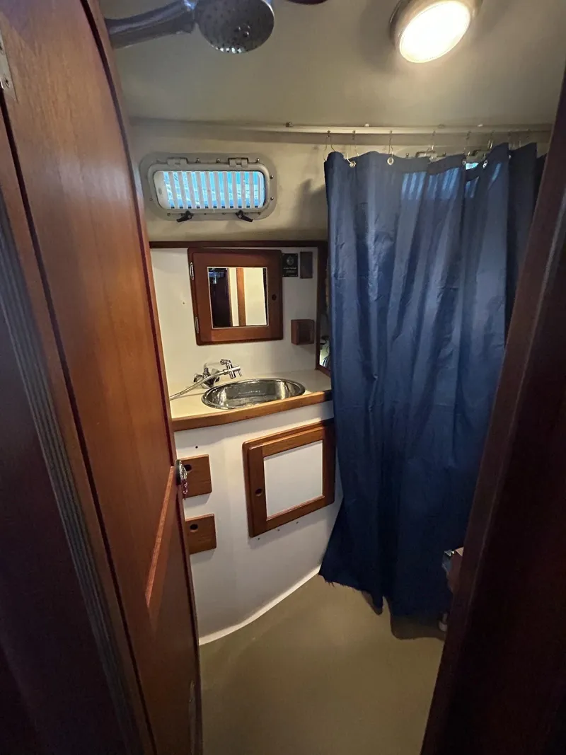 Slide: The Image of 1991 Freedom F-38 yacht bathroom with sink, mirror, and blue shower curtain. - 20