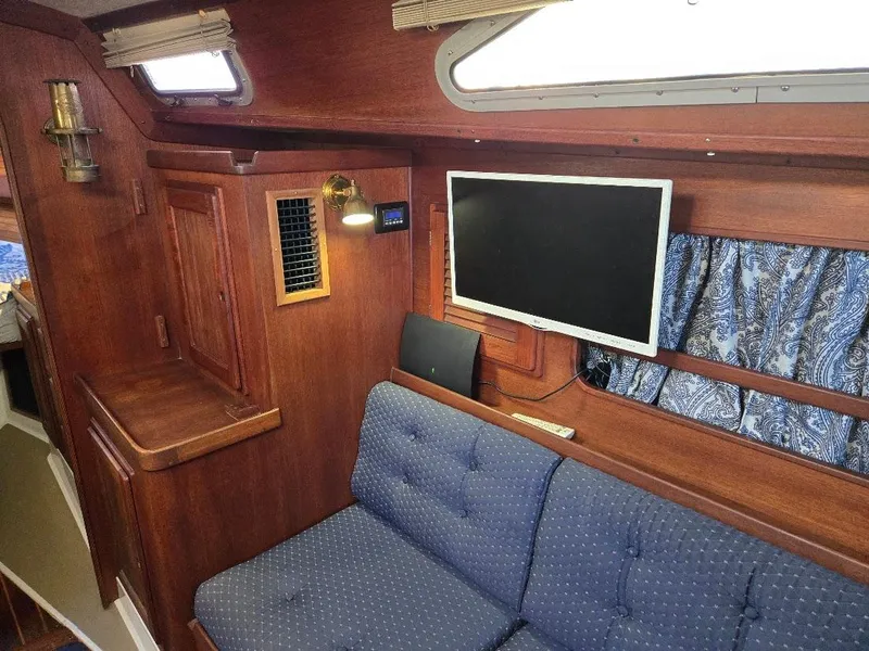 Slide: The Image of Interior of 1991 Freedom F-38 yacht with wood paneling, blue sofa, and mounted TV. - 23