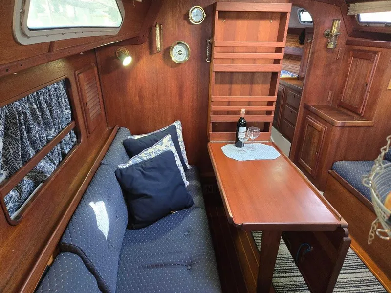 Slide: The Image of Cozy 1991 Freedom F-38 yacht interior with wooden decor, dining area, and wine setup. - 25