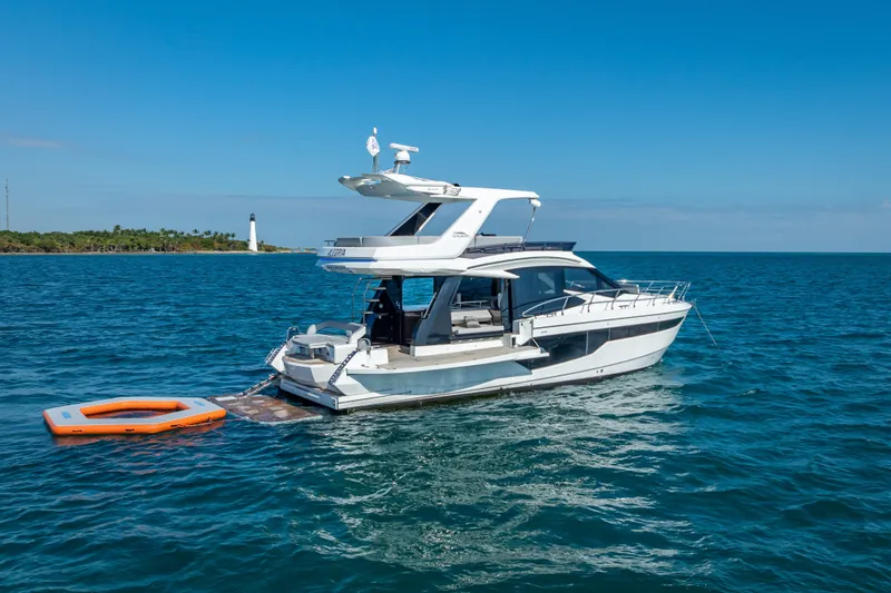 Slide: The Image of 2021 Galeon 500 Fly yacht on open sea with lighthouse in background. - 1