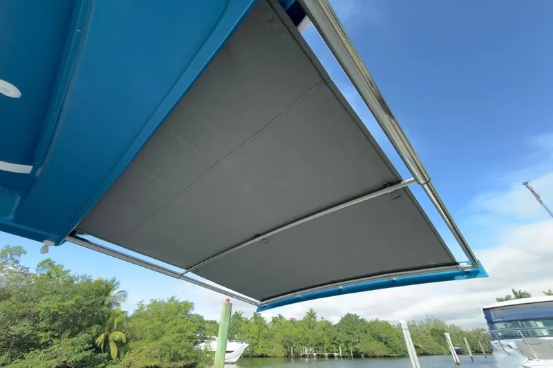 Slide: The Image of 2022 Intrepid 407 Panacea boat with extended sunshade, docked near lush greenery. - 149