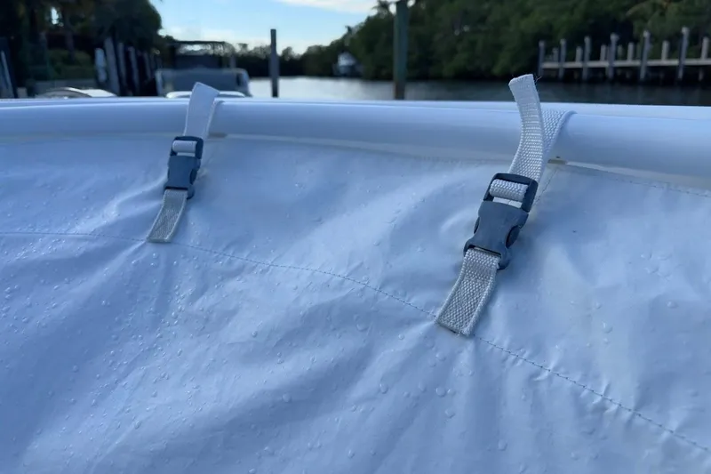 Slide: The Image of 2022 Intrepid 407 Panacea boat cover with secure straps, docked by a serene waterway. - 22