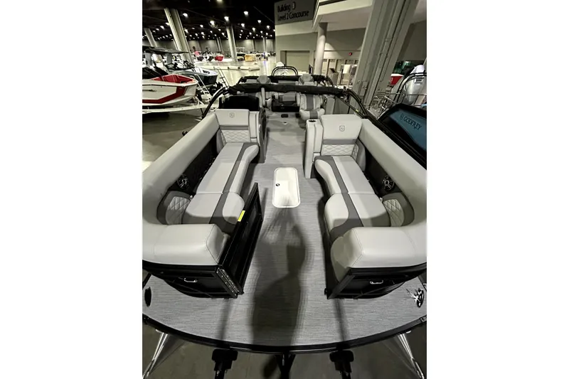 Slide: The Image of 2026 Godfrey Monaco 255 QSL pontoon boat interior with luxurious seating at a boat show. - 8