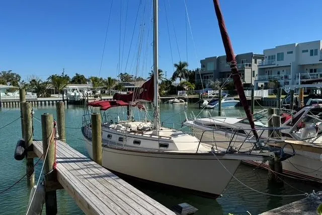 Slide: The Image of 1989 Island Packet 35 sailboat docked in a marina with modern buildings in the background. - 1