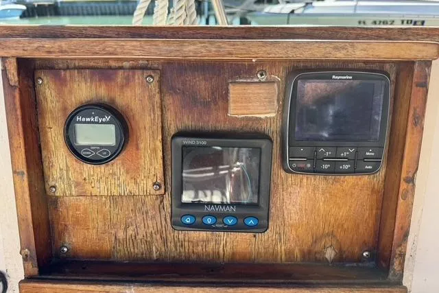 Slide: The Image of Wooden dashboard with HawkEye, Navman, and Raymarine instruments on a 1989 Island Packet 35 sailboat. - 13