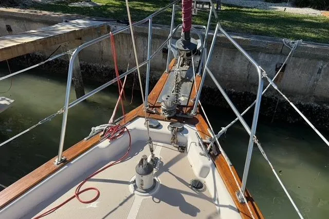 Slide: The Image of Bow of 1989 Island Packet 35 sailboat docked, featuring deck hardware and railing. - 21