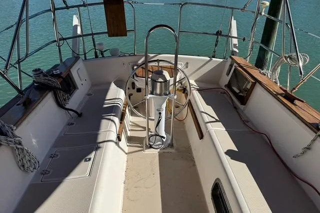 Slide: The Image of 1989 Island Packet 35 sailboat cockpit with steering wheel, seating, and ocean view. - 4