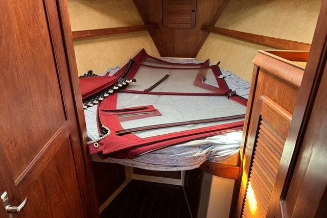 Slide: The Image of 1989 Island Packet 35 cabin interior with folded red sails on bed. - 40