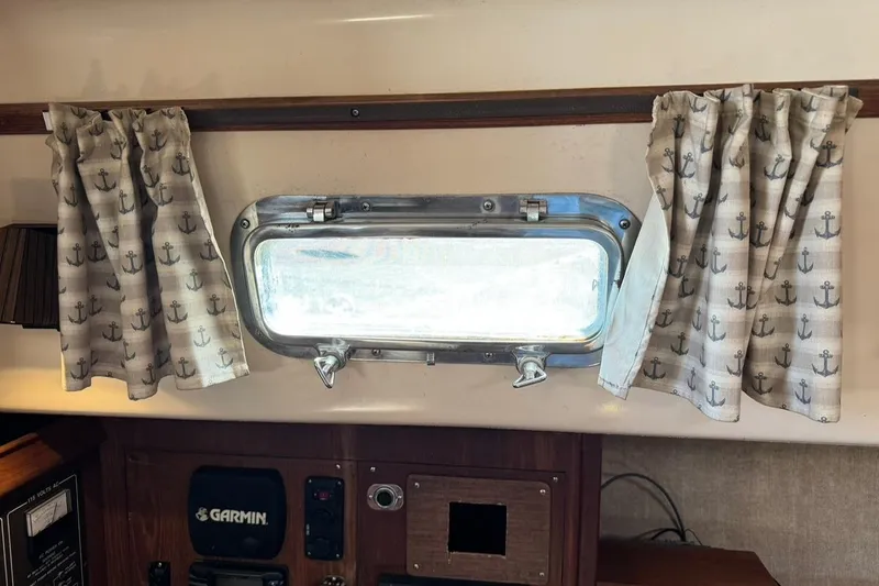 Slide: The Image of 1989 Island Packet 35 interior with nautical curtains and porthole window. - 52