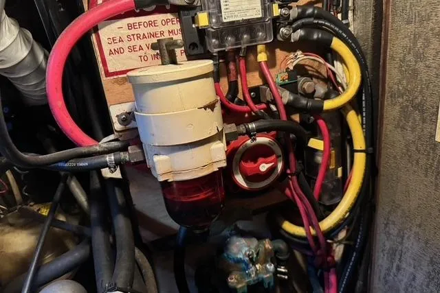 Slide: The Image of Engine compartment of a 1989 Island Packet 35 sailboat, featuring wiring and fuel filter system. - 55