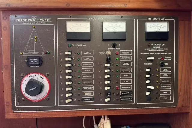 Slide: The Image of Control panel of a 1989 Island Packet 35 yacht, featuring voltage meters and switches. - 57