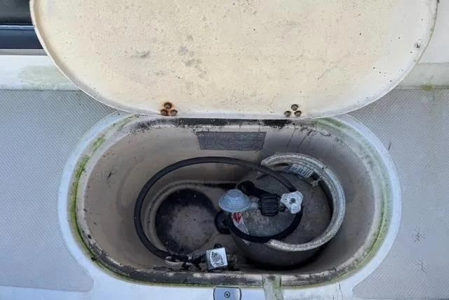 Slide: The Image of Open storage compartment on 1989 Island Packet 35 sailboat, showing propane tank and hose. - 7