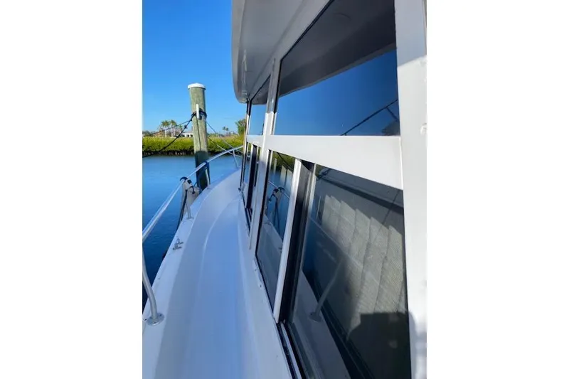 Slide: The Image of 1999 Mainship 350 Trawler side view, docked on calm water under clear blue sky. - 19