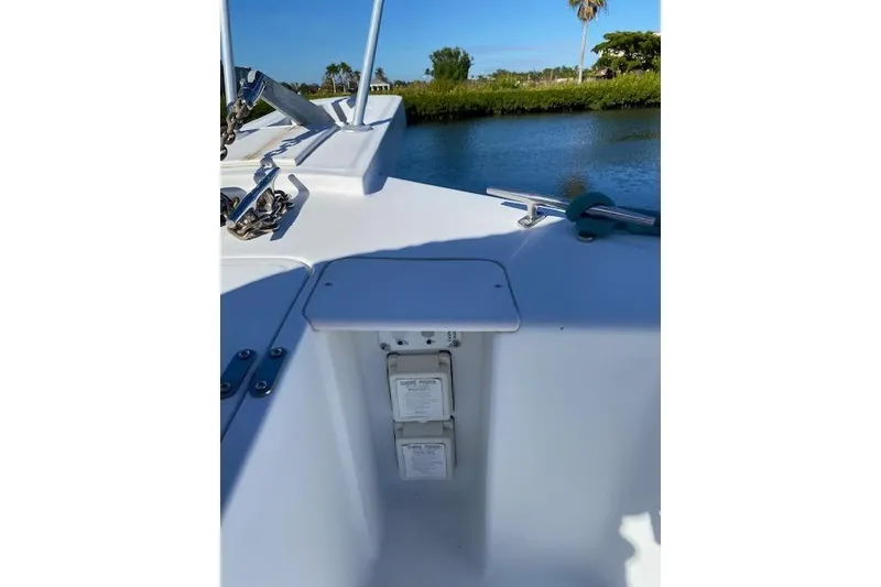 Slide: The Image of 1999 Mainship 350 Trawler deck with shore power outlets, docked by a scenic waterway. - 23