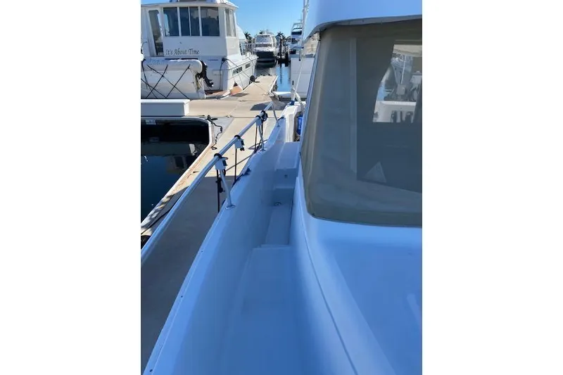 Slide: The Image of 1999 Mainship 350 Trawler docked, showcasing side deck and railing. - 25