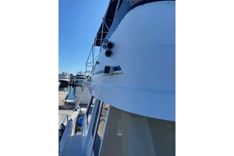 Slide: The Image of 1999 Mainship 350 Trawler docked, showcasing sleek white exterior and nautical design. - 26